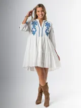 Vestido corto blanco de algodón italiano con bordado azul, mangas tres cuartos y botones frontales.
