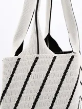 Bolso tipo tote de tejido de punto color crudo con diseño de líneas diagonales negras formando figuras geométricas. Tiene doble asa corta de hombro.