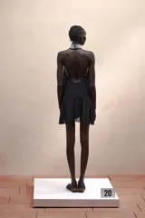 Vestido corto negro con cuello halter con joyas, caída amplia y espalda descubierta.