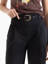 Pantalón negro de tiro alto, estilo mom fit, confeccionado en poplin con spandex. Presenta tablas en la cintura con cinto de hebilla de cadena dorada, canesú y pinzas delanteras.