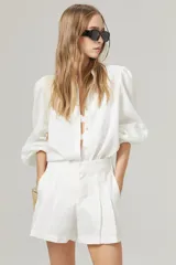 Camisa blanca de lino con cuello mao, mangas largas abullonadas con puño elástico y corte holgado.