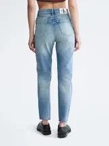 Jean de denim celeste con efecto desgastado y roturas, de corte mom, tiro alto y cinco bolsillos.