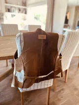 Chaleco de cuero con estampado de vaca, detalles de punto cruz y flecos.