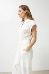 Mono largo blanco con broderie, corte palazzo, cuello camisero, mangas cortas y cinturón de lazo.