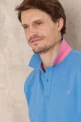 Chomba azul con cuello clásico, tapeta de dos botones y logo bordado en el pecho.