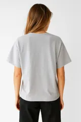 Remera de manga corta color blanco, corte holgado y cuello redondo. Presenta un estampado frontal con un diseño de sello postal con flores de cerezo.