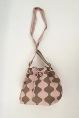 Bolso tipo bombonera tejido a crochet, con patrón geométrico en tonos rosa y marrón. Tiene cierre con cordón ajustable y correa de hombro.