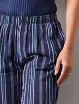 Pantalón capri de algodón estampado a rayas verticales en tonos celeste, rosa y beige. Tiene pretina elastizada, bolsillos delanteros y tajos laterales con botones.