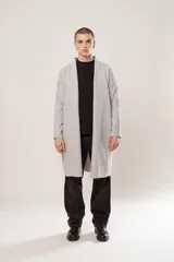 Sacón largo gris melange de tela simil paño, calce regular, con terminación al corte en mangas y ruedo, y bolsillos ocultos.
