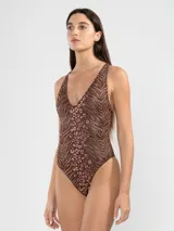 Malla entera marrón con estampado animal print, escote en V, espalda descubierta con tiras cruzadas y detalle metálico cuadrado.