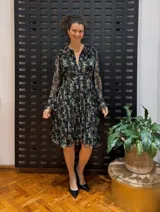 Vestido midi negro con estampado floral, mangas largas y cuello con volantes plisados.