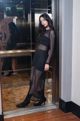Vestido de malla negra con detalles brillantes, de manga larga y diseño ajustado.