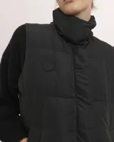 Chaleco acolchado color beige con cuello alto y cierre frontal.