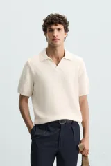 Polo color crema de punto con cuello solapa y abertura frontal en V.