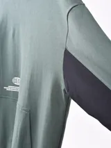 Buzo hoodie color petróleo con bolsillo tipo canguro y estampado blanco con forma de globo terráqueo y texto.