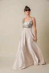 Vestido largo de fiesta color champagne, con corpiño de lentejuelas plateadas, falda de satén liso y lazo de satén en la cintura. Corsé de tul bordado. Talle único adaptable de S a L.