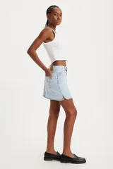 Falda corta de denim color celeste claro, con cierre frontal de botones y talle medio. Presenta un diseño asimétrico con un corte en el ruedo lateral.
