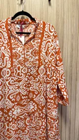 Vestido amplio color naranja con estampado blanco, cuello mao y mangas 3/4.