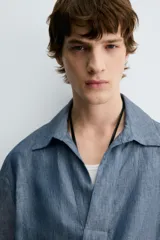 Camisa azul de lino con cuello polo, corte holgado y mangas cortas.