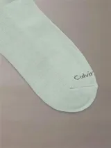 Pack de tres pares de medias Calvin Klein, una blanca, una gris y una verde claro, con logo CK en el tobillo.