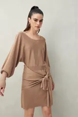 Vestido corto negro de punto con brillo sutil, mangas largas amplias, falda ajustada y lazo frontal en la cintura.