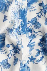 Blusa blanca con estampado floral azul, cuello redondo, cierre de botones y mangas globo tres cuartos con puños elásticos.