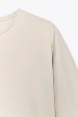 Camiseta color beige de corte amplio, cuello redondo y mangas cortas.