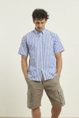 Camisa de manga corta a rayas verticales azules y blancas, con cuello abotonado y bolsillo en el pecho.
