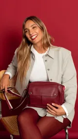 Bandolera bordeaux de cuero sintético con apertura central con cierre metálico. Tiene un bolsillo principal con cierre y un bolsillo frontal con tapa y broches magnéticos. Incluye bolsillos internos y posterior, y correa de galón combinada larga y regulable.