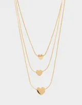 Collar dorado multicadena con tres cadenas de diferentes largos, cada una con un dije de corazón.