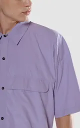 Camisa celeste de manga corta con doble bolsillo y ojal delantero con solapa en uno de ellos. Tiene calce oversize y está realizada en tejido plano suave al tacto.