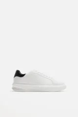 Zapatillas urbanas blancas con detalle de pieza a contraste en la parte posterior color negro y suela con volumen de diseño irregular.