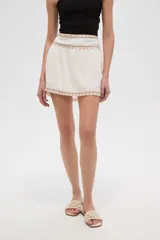 Minifalda azul marino con elástico fruncido en la cintura y el ruedo, ambos adornados con una banda de bordado étnico en tonos rosados y morados.