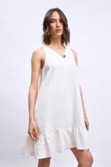 Vestido corto sin mangas, color celeste claro, con escote en V y un pequeño broche decorativo en la abertura frontal. Presenta un corte holgado tipo babydoll con bolsillos laterales y un ruedo con volado.