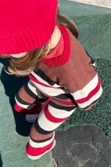 Sweater de punto color marrón con rayas horizontales en blanco, negro y rojo.