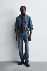 Camisa relaxed fit confeccionada en denim de algodón con cuello solapa, manga larga con puño abotonado, efecto lavado medio y cierre frontal con botones.