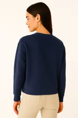 Buzo negro de cuello redondo y manga larga, con estampado frontal de la palabra "PARIS" en color lila con borde blanco.