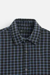 Camisa de hombre a cuadros azules y negros, de corte cuadrado, con cuello solapa, manga larga con puños abotonados, cierre frontal con botones y bolsillos de parche con solapa en el pecho.