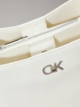 Cartera estilo bucket de piel sintética color blanco, con textura tejida similar al lino. Presenta herrajes metálicos y el monograma 'CK' en la parte frontal. Cuenta con correas de hombro ajustables.
