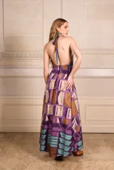 Vestido largo con estampado geométrico en tonos violeta, marrón y celeste, con cuello halter y espalda descubierta.