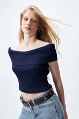 Top tejido color blanco con escote bardot que deja los hombros al descubierto y punto acanalado.