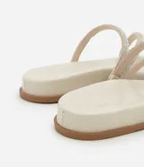 Sandalia plana mule color crema con punta redonda y tiras finas con brillos.