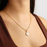 Collar dorado con dije redondo con el signo zodiacal de capricornio.