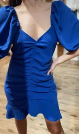 Vestido corto azul eléctrico con escote en V, mangas abullonadas 3/4, frunce central y volados en el ruedo.