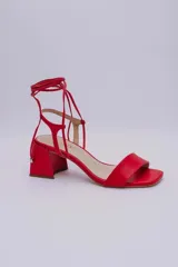Sandalias rojas de cuero con tiras finas para atar al tobillo y tacón cuadrado.