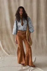 Pantalón de jean acampanado color caramelo, de tiro alto y corte ajustado en la parte superior. Presenta bolsillos delanteros y traseros, y ruedo acampanado con vuelo.