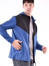 Campera deportiva azul con paneles negros en la parte superior y capucha. Cierre frontal con cremallera.