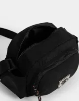 Bandolera negra de tela deportiva con correa regulable, cierre superior, bolsillos laterales, bolsillo frontal con cierre y tag de goma.