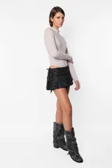 Minifalda gris con estampado de cuadros escoceses, cintura ancha, tablas en la parte inferior y cierre metálico lateral. Incluye sobrefalda desmontable con bolsillo.