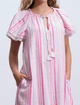 Vestido corto de lino a rayas verticales color lila y blanco, con cuello fruncido, escote en V y lazo de ajuste. Mangas cortas con puntilla de crochet.